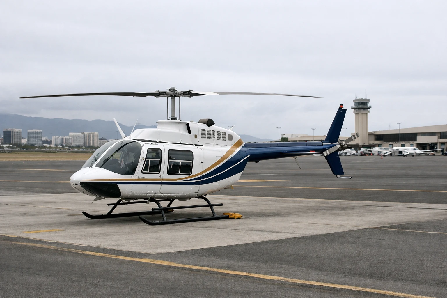 Bell 206B helicopter parked on an airport ramp in Honolulu under overcast daylight
