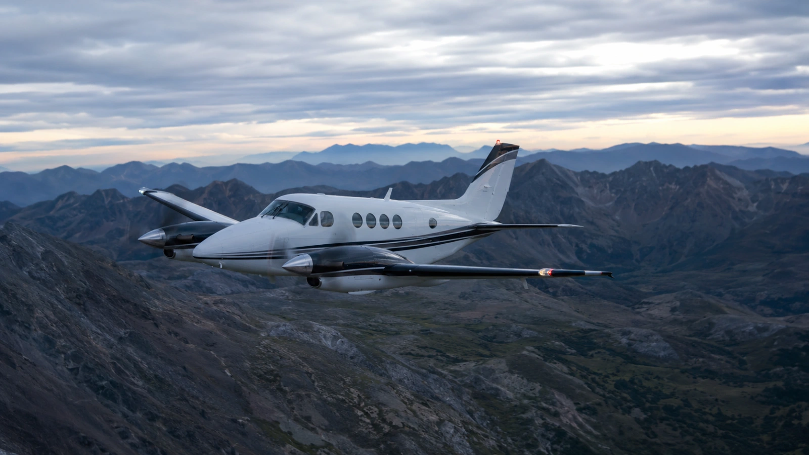 Beechcraft King Air 90 flying over mountainous terrain